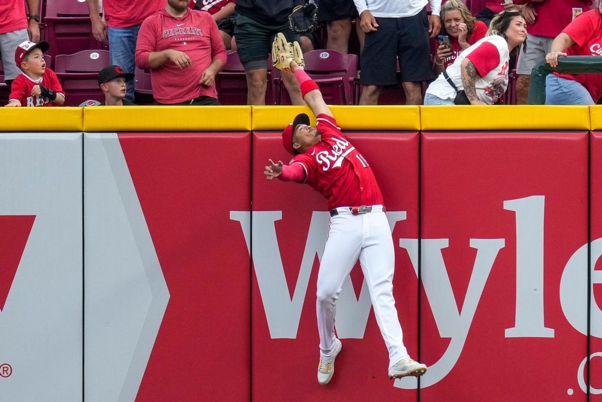 Cincinnati Reds third baseman Noelvi Marte (16) leaps to rob a home run over the wall from Pittsburgh Pirates right fielder Bryan Reynolds (10) in the ninth inning of the MLB National League game between the Cincinnati Reds and the Pittsburgh Pirates at Great American Ball Park in downtown Cincinnati on Thursday, Sept. 25, 2025. The Reds won, 2-1.