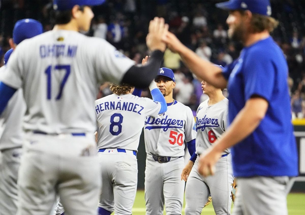 Los Angeles Dodgers shortstop Mookie Betts (50) high-fives first baseman Enrique Hernandez (8) after defeating the Arizona Diamondbacks 8-0 to clinch the National League West title during the season home finale at Chase Field in Phoenix on Sept. 25, 2025.