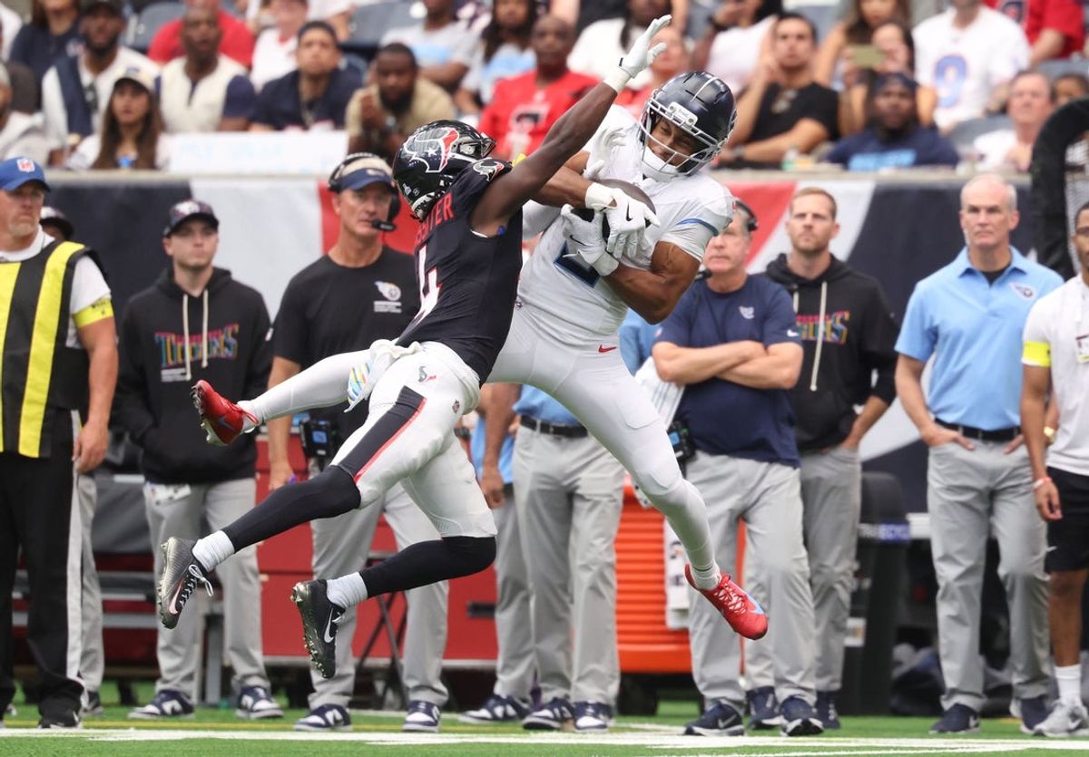Sep 28, 2025; Houston, Texas, USA; Tennessee Titans wide receiver Elic Ayomanor (5) makes a catch against Houston Texans cornerback Kamari Lassiter (4) during the first half at NRG Stadium. Mandatory Credit: Troy Taormina-Imagn Images