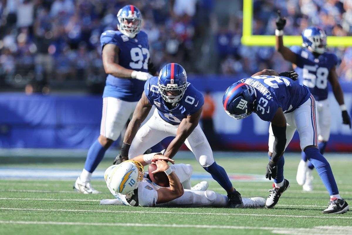 Sep 28, 2025; East Rutherford, New Jersey, USA;  Los Angeles Chargers quarterback Justin Herbert (10) is sacked by New York Giants linebacker Brian Burns (0) during the fourth quarter at MetLife Stadium. Mandatory Credit: Brad Penner-Imagn Images
