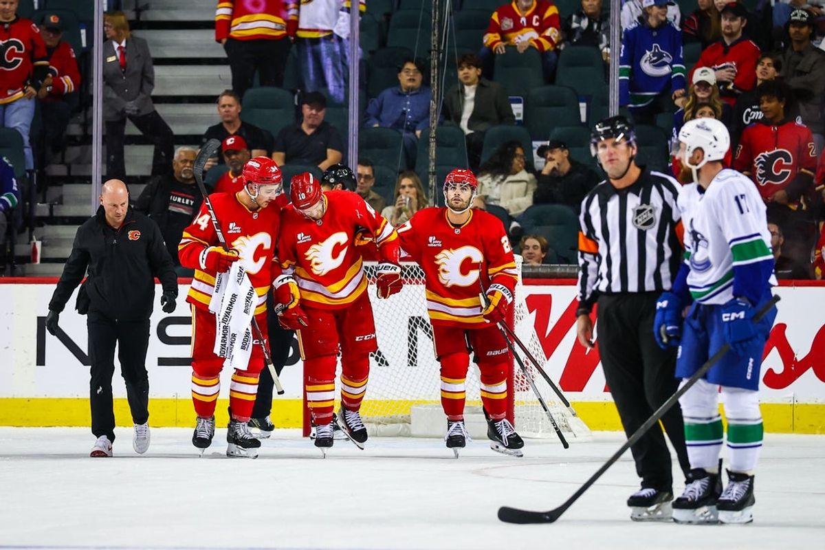 Oct 1, 2025; Calgary, Alberta, CAN; Calgary Flames left wing Jonathan Huberdeau (10) gets help off the ice after colliding with Vancouver Canucks goaltender Kevin Lankinen (32) during the third period at Scotiabank Saddledome. Mandatory Credit: Sergei Belski-Imagn Images