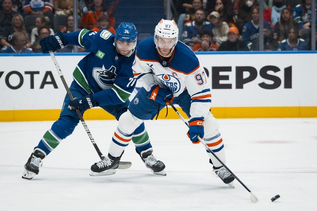Oct 3, 2025; Vancouver, British Columbia, CAN; Vancouver Canucks forward Jake DeBrusk (74) defends against Edmonton Oilers forward Connor McDavid (97) in the second period at Rogers Arena. Mandatory Credit: Bob Frid-Imagn Images