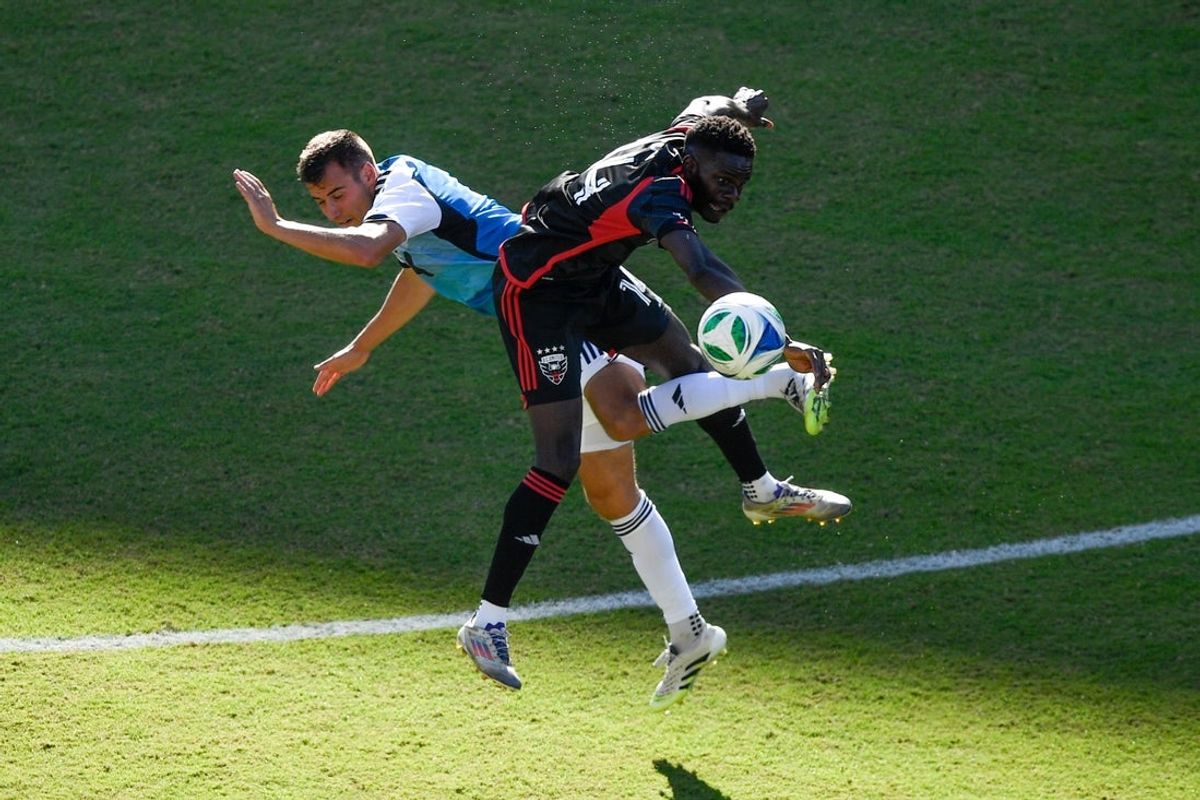 Oct 4, 2025; Washington, District of Columbia, USA; Charlotte FC midfielder Andrew Privett (4) and D.C. United forward Dominique Badji (14) go after the ball during the second half of the game at Audi Field. Mandatory Credit: Hannah Foslien-Imagn Images