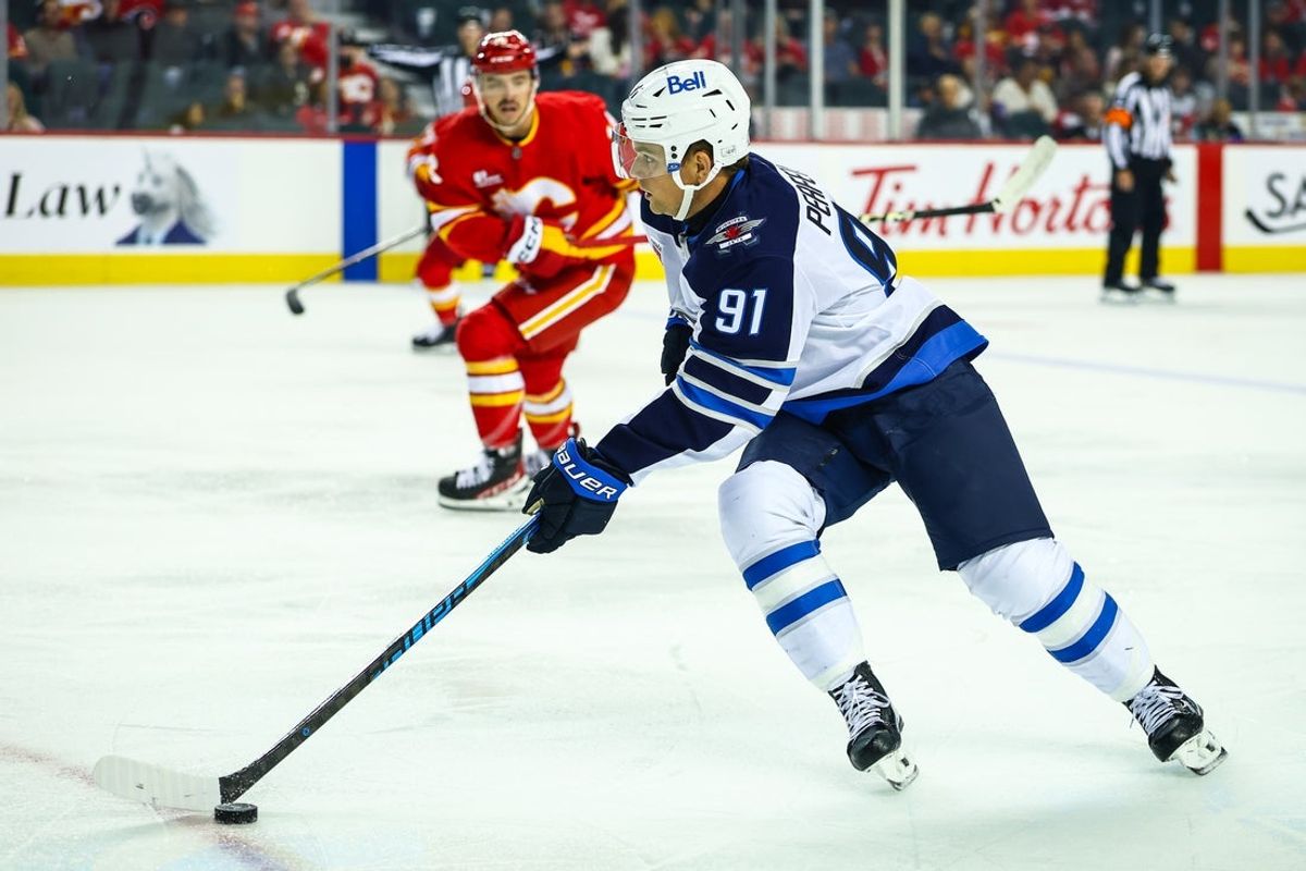 Oct 3, 2025; Calgary, Alberta, CAN; Winnipeg Jets center Cole Perfetti (91) skates with the puck against the Calgary Flames during the first period at Scotiabank Saddledome. Mandatory Credit: Sergei Belski-Imagn Images