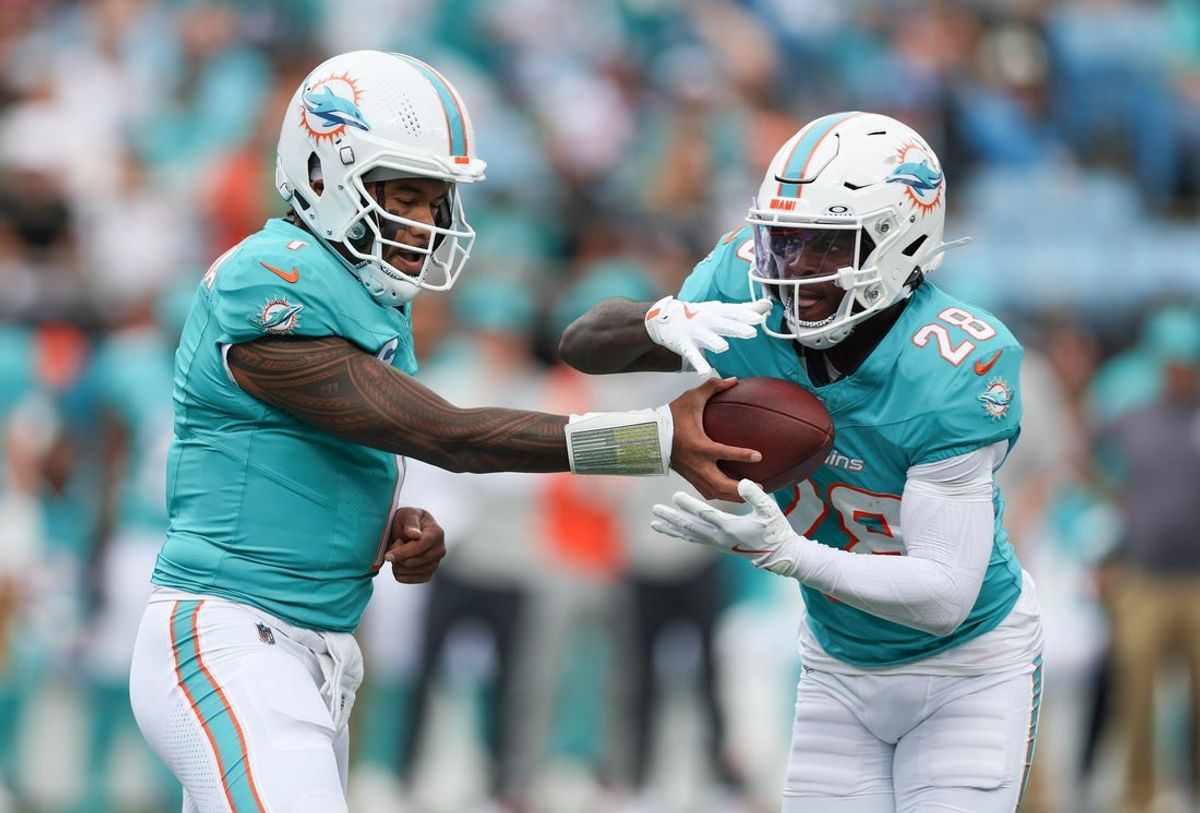 Oct 5, 2025; Charlotte, North Carolina, USA; Miami Dolphins quarterback Tua Tagovailoa (1) hands off the ball to Miami Dolphins running back De'Von Achane (28) during the first quarter against the Carolina Panthers at Bank of America Stadium. Mandatory Credit: Cory Knowlton-Imagn Images