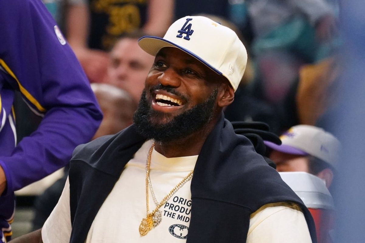 Oct 5, 2025; San Francisco, California, USA;  Los Angeles Lakers forward LeBron James (23), wearing a Los Angeles Dodgers hat, smiles after watching his son, guard Bronny James (9), dunk a rebound against the Golden State Warriors in the third quarter at Chase Center. Mandatory Credit: David Gonzales-Imagn Images