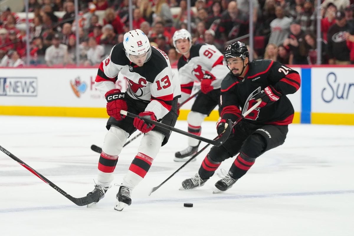 Oct 9, 2025; Raleigh, North Carolina, USA;  New Jersey Devils center Nico Hischier (13) cuts with the puck inside of Carolina Hurricanes center Seth Jarvis (24) during the second period at Lenovo Center. Mandatory Credit: James Guillory-Imagn Images