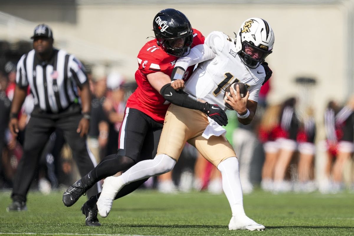 Oct 11, 2025; Cincinnati, Ohio, USA; Cincinnati Bearcats linebacker Jake Golday (11) attempts to tackle UCF Knights quarterback Cam Fancher (14) in the second half at Nippert Stadium. Mandatory Credit: Aaron Doster-Imagn Images