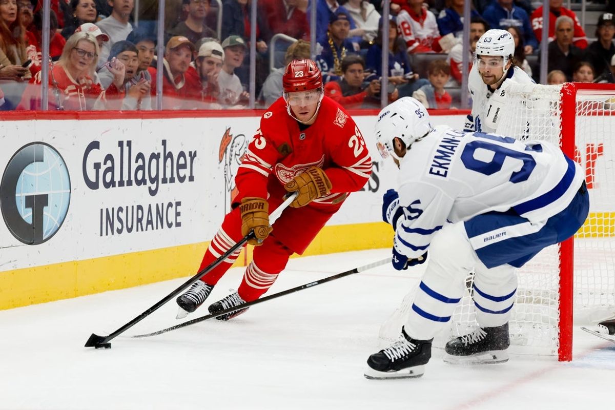 Oct 11, 2025; Detroit, Michigan, USA;  Detroit Red Wings left wing Lucas Raymond (23) skates with the puck defended by Toronto Maple Leafs defenseman Oliver Ekman-Larsson (95) in the second period at Little Caesars Arena. Mandatory Credit: Rick Osentoski-Imagn Images