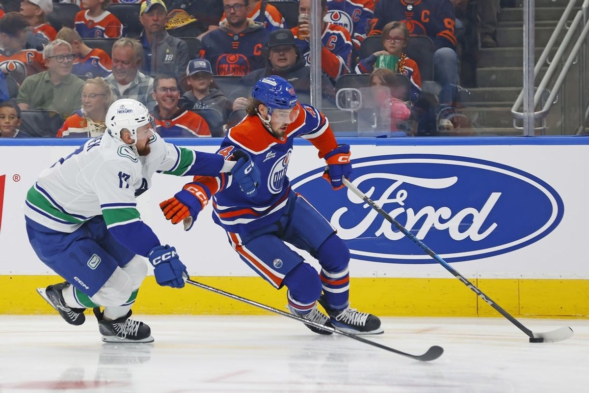 Oct 11, 2025; Edmonton, Alberta, CAN; Vancouver Canucks defensemen Filip Hornek (17) tries to knock the puck away from Edmonton Oilers forward Noah Philp (48) during the first period at Rogers Place. Mandatory Credit: Perry Nelson-Imagn Images