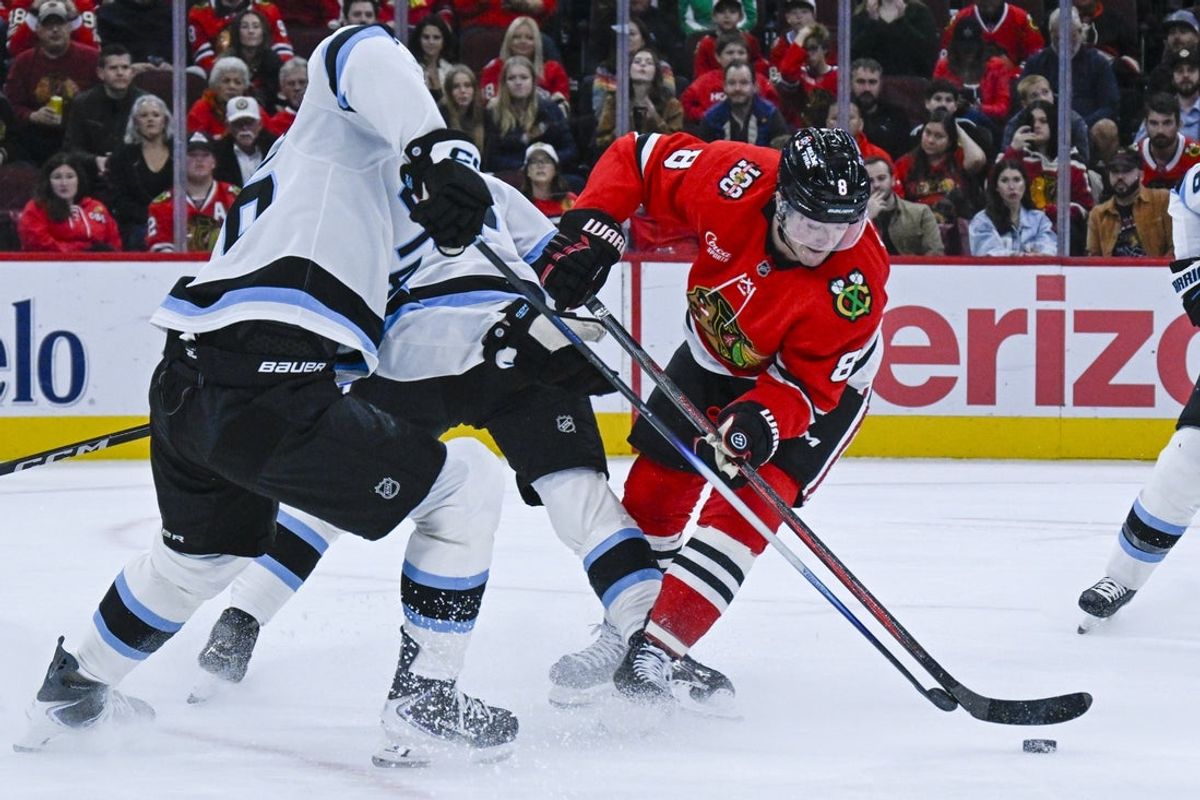 Oct 13, 2025; Chicago, Illinois, USA;  Chicago Blackhawks center Ryan Donato (8) and Utah Mammoth defenseman Dmitri Simashev (26) chase the puck during the first period at United Center. Mandatory Credit: Matt Marton-Imagn Images