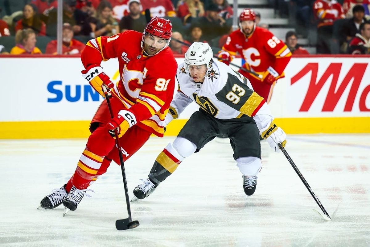 Oct 14, 2025; Calgary, Alberta, CAN; Calgary Flames center Nazem Kadri (91) controls the puck against Vegas Golden Knights right wing Mitch Marner (93) during the third period at Scotiabank Saddledome. Mandatory Credit: Sergei Belski-Imagn Images