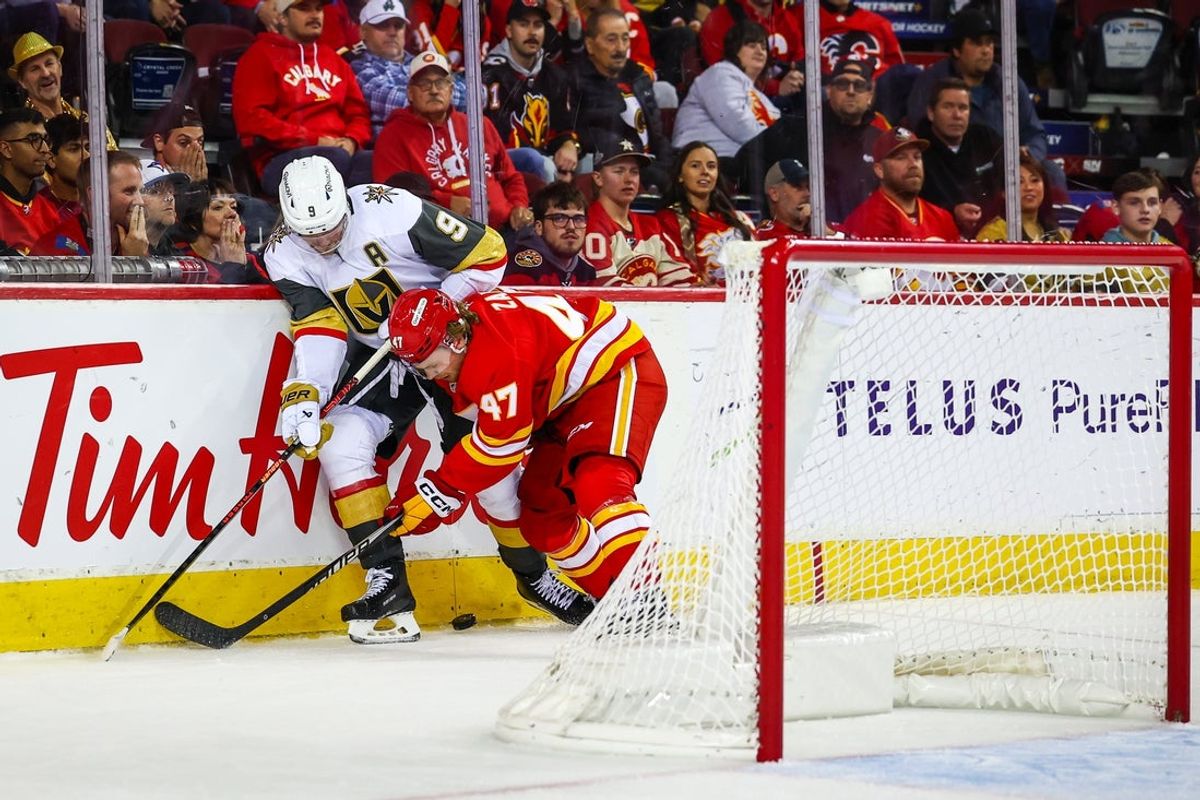 Oct 14, 2025; Calgary, Alberta, CAN; Vegas Golden Knights center Jack Eichel (9) and Calgary Flames center Connor Zary (47) battles for the puck behind the empty Calgary Flames net during the third period at Scotiabank Saddledome. Mandatory Credit: Sergei Belski-Imagn Images