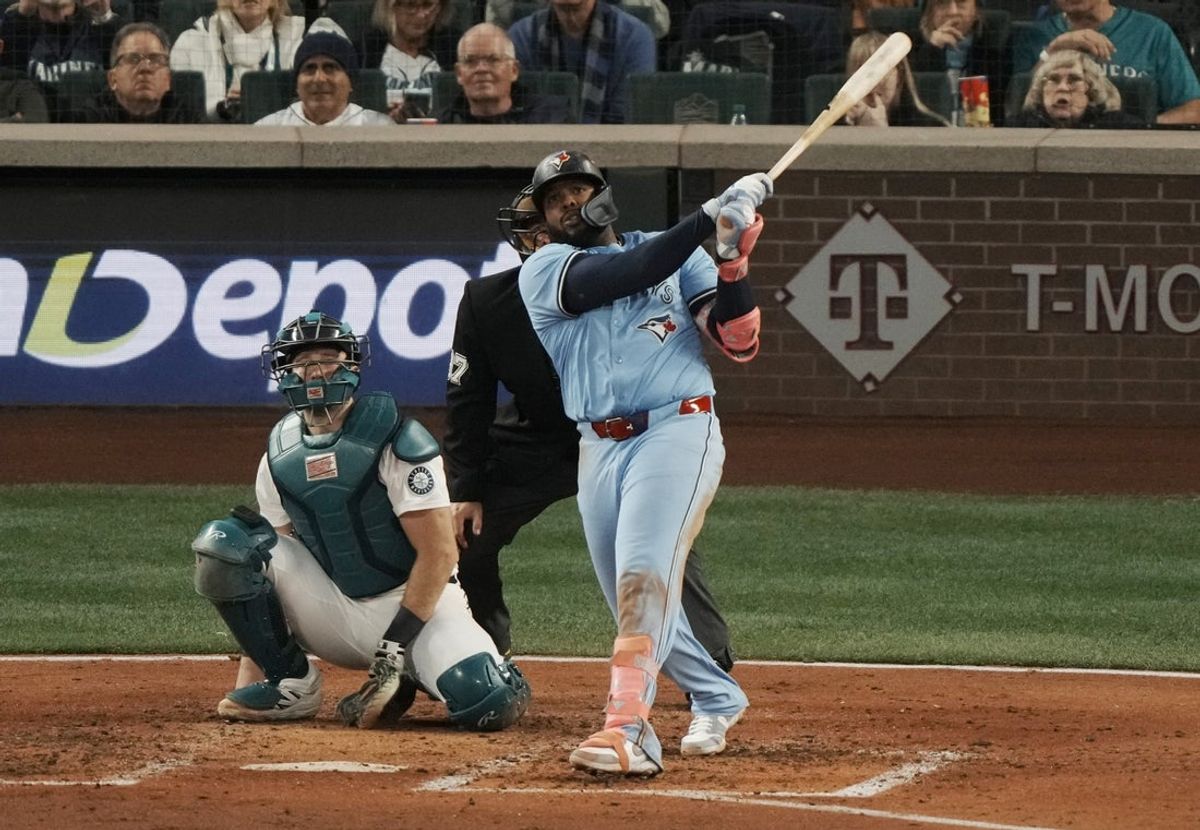 Oct 15, 2025; Seattle, Washington, USA; Toronto Blue Jays first baseman Vladimir Guerrero Jr. (27) hits a home run in front of Seattle Mariners catcher Cal Raleigh (29) in the fifth inning during game three of the ALCS round for the 2025 MLB playoffs at T-Mobile Park. Mandatory Credit: Stephen Brashear-Imagn Images