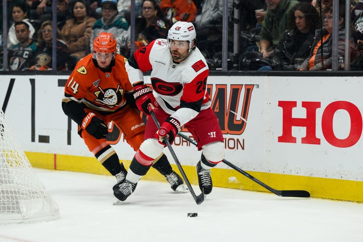 Oct 16, 2025; Anaheim, California, USA; Carolina Hurricanes left wing William Carrier (28) looks to pass while under pressure from Anaheim Ducks defenseman Drew Helleson (14) during the first period at Honda Center. Mandatory Credit: William Liang-Imagn Images