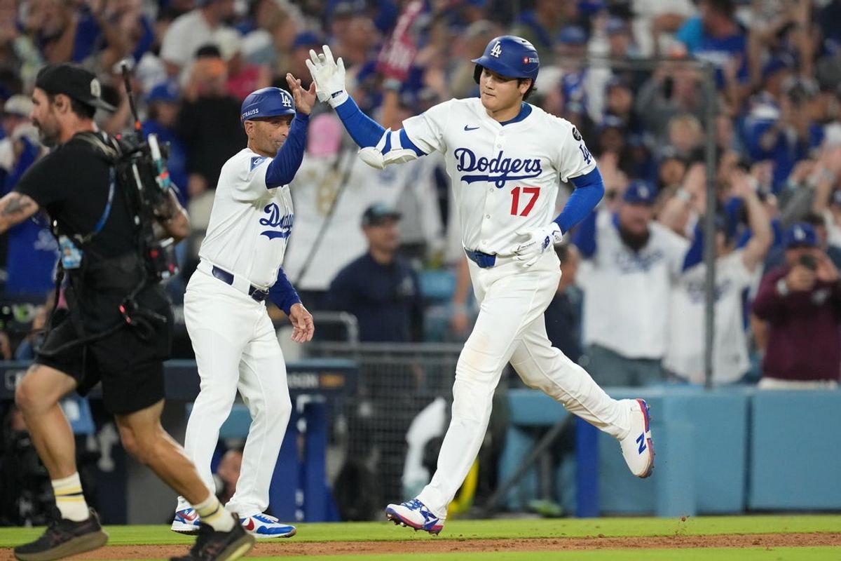 Oct 17, 2025; Los Angeles, California, USA; Los Angeles Dodgers two-way player Shohei Ohtani (17) celebrates with third base coach/outfield coach Dino Ebel (91) as he runs home to score after hitting a solo home run against the Milwaukee Brewers in the seventh inning during game four of the NLCS round for the 2025 MLB playoffs at Dodger Stadium. Mandatory Credit: Kirby Lee-Imagn Images