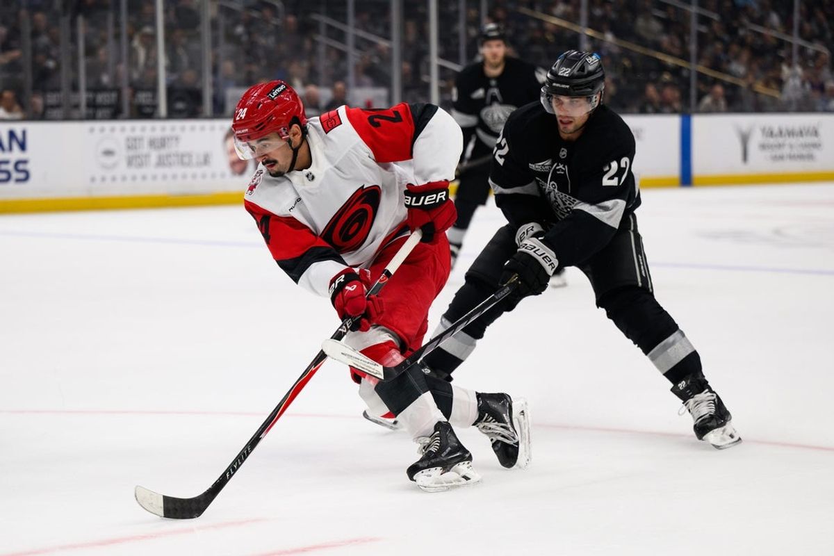 Oct 18, 2025; Los Angeles, California, USA; Carolina Hurricanes center Seth Jarvis (24) skates the puck past Los Angeles Kings left wing Kevin Fiala (22) during the first period at Crypto.com Arena. Mandatory Credit: William Liang-Imagn Images