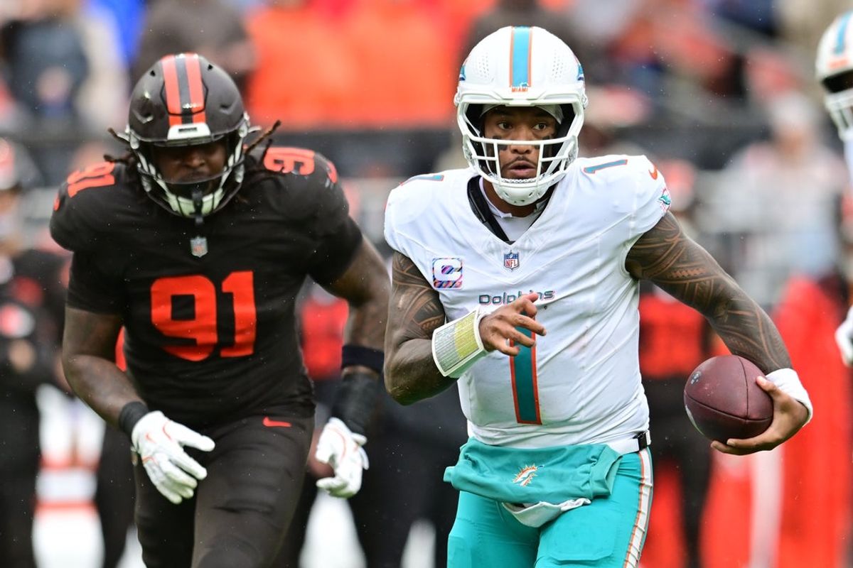Oct 19, 2025; Cleveland, Ohio, USA; Miami Dolphins quarterback Tua Tagovailoa (1) runs with the ball as Cleveland Browns defensive end Alex Wright (91) defends during the first half at Huntington Bank Field. Mandatory Credit: Ken Blaze-Imagn Images