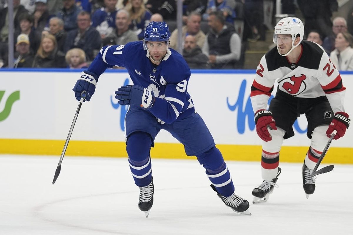 Oct 21, 2025; Toronto, Ontario, CAN; Toronto Maple Leafs forward John Tavares (91) and New Jersey Devils defenseman Brett Pesce (22) chase a loose puck during the first period at Scotiabank Arena. Mandatory Credit: John E. Sokolowski-Imagn Images