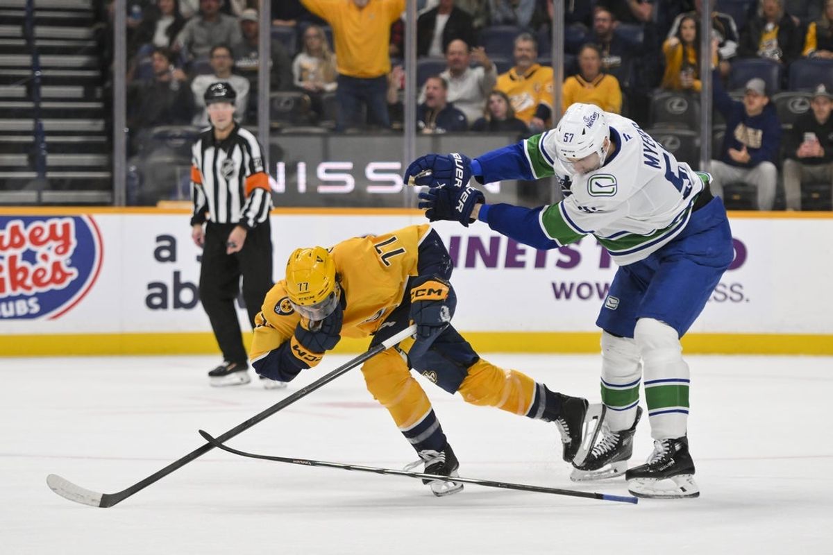Oct 23, 2025; Nashville, Tennessee, USA;  Vancouver Canucks defenseman Tyler Myers (57) shoves Nashville Predators right wing Luke Evangelista (77) after checking Jim during the third period at Bridgestone Arena. Mandatory Credit: Steve Roberts-Imagn Images