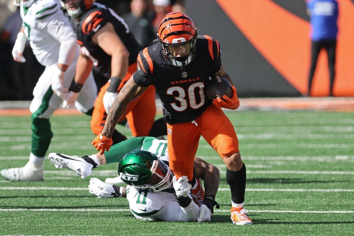 Oct 26, 2025; Cincinnati, Ohio, USA; Cincinnati Bengals running back Chase Brown (30) escapes the attack from New York Jets linebacker Jermaine Johnson (11) during the second quarter at Paycor Stadium. Mandatory Credit: Joseph Maiorana-Imagn Images