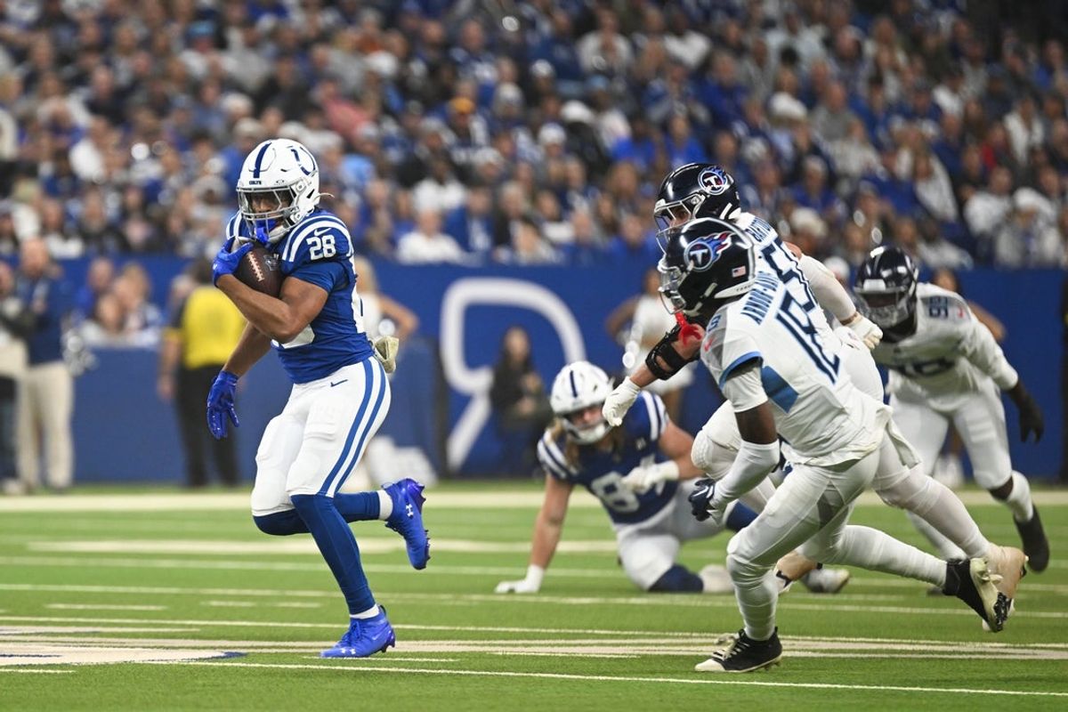 Oct 26, 2025; Indianapolis, Indiana, USA; Indianapolis Colts running back Jonathan Taylor (28) rushes as Tennessee Titans cornerback Jalyn Armour-Davis (18) defends during the first quarter at Lucas Oil Stadium. Mandatory Credit: Robert Goddin-Imagn Images
