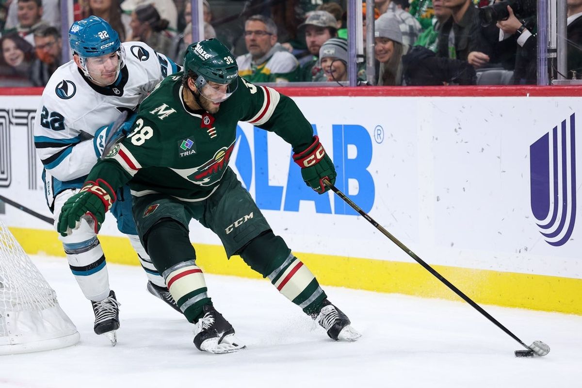 Oct 26, 2025; Saint Paul, Minnesota, USA; Minnesota Wild right wing Ryan Hartman (38) skates with the puck alongside San Jose Sharks defenseman Vincent Lorio (22) during the third period at Grand Casino Arena. Mandatory Credit: Matt Krohn-Imagn Images