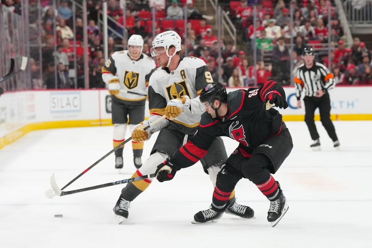 Oct 28, 2025; Raleigh, North Carolina, USA;  Carolina Hurricanes defenseman Domenick Fensore (89) pokes the puck away from Vegas Golden Knights center Jack Eichel (9) during the second period at Lenovo Center. Mandatory Credit: James Guillory-Imagn Images