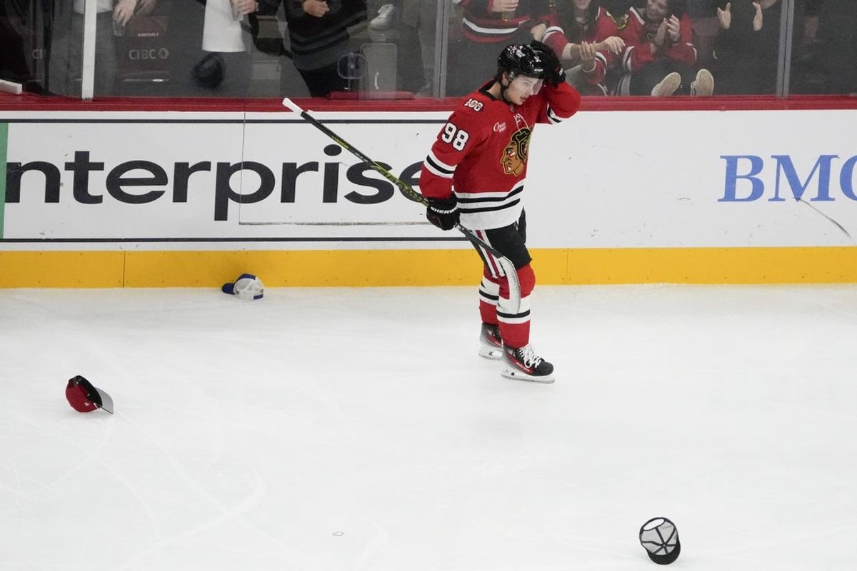 Oct 28, 2025; Chicago, Illinois, USA; Chicago Blackhawks center Connor Bedard (98) picks up hats with his stick as he celebrates his hat trick against the Ottawa Senators during the third period at United Center. Mandatory Credit: David Banks-Imagn Images