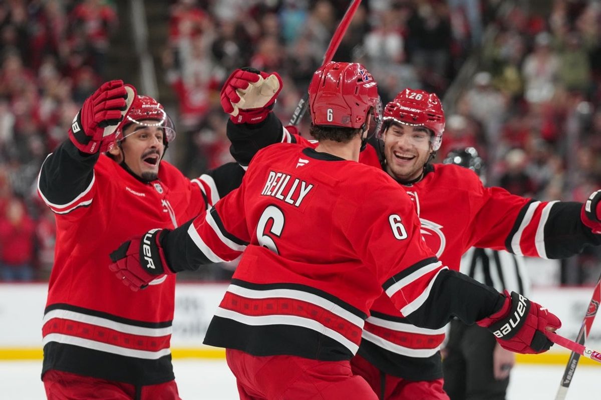 Oct 30, 2025; Raleigh, North Carolina, USA;  Carolina Hurricanes defenseman Mike Reilly (6) celebrates his goal witb center Seth Jarvis (24) and  defenseman Sean Walker (26) against the New York Islanders during the first period at Lenovo Center. Mandatory Credit: James Guillory-Imagn Images