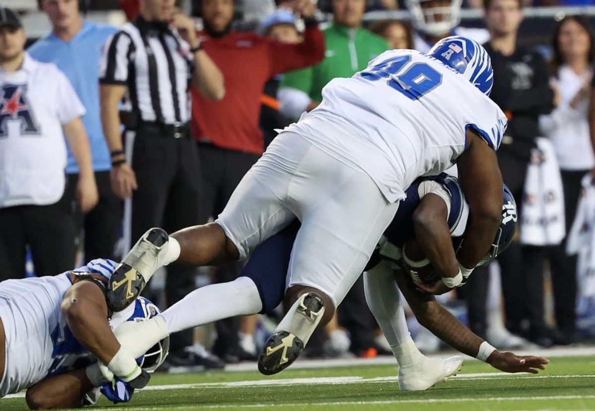Oct 31, 2025; Houston, Texas, USA; Rice Owls quarterback Chase Jenkins (4) is sacked by Memphis Tigers defensive lineman Pooda Walker (99) in the first quarter at Rice Stadium. Mandatory Credit: Thomas Shea-Imagn Images