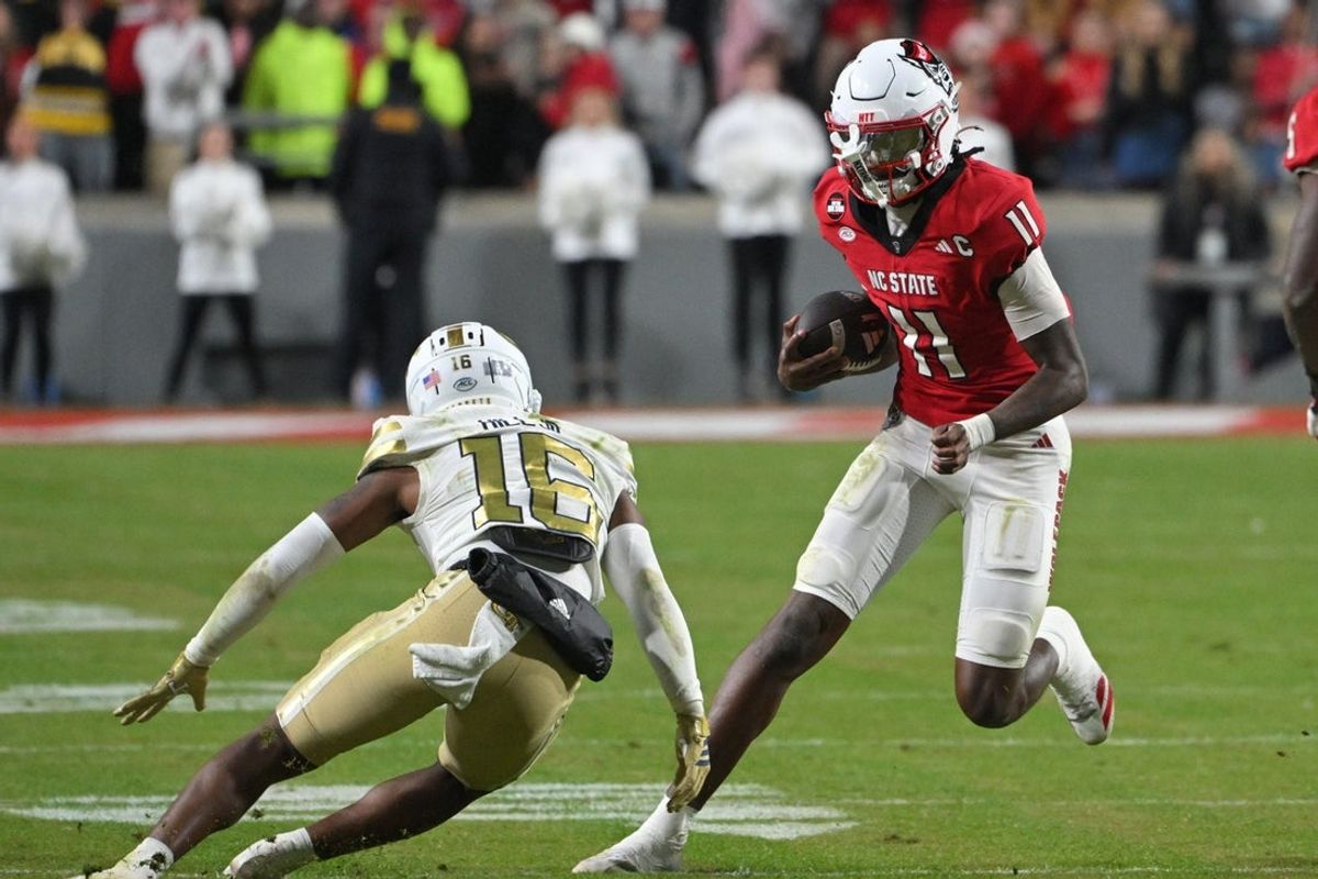 Nov 1, 2025; Raleigh, North Carolina, USA;  North Carolina State Wolfpack quarter back CJ Bailey (11) runs the ball against Georgia Tech Yellow Jackets defensive back Kelvin Hill (16) during the fourth quarter at Carter-Finley Stadium. Mandatory Credit: Zachary Taft-Imagn Images