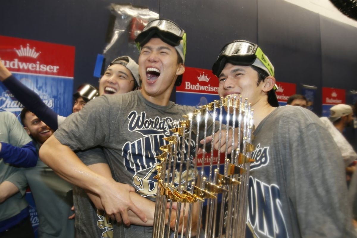 Oct 31, 2025; Toronto, Ontario, CAN; Los Angeles Dodgers two-way player Shohei Ohtani (17) and pitcher Yoshinobu Yamamoto (18) and pitcher Roki Sasaki (11) celebrate with the Commissioner's Trophy in the clubhouse after defeating the Toronto Blue Jays in the 2025 MLB World Series at Rogers Centre. Mandatory Credit: John E. Sokolowski-Imagn Images
