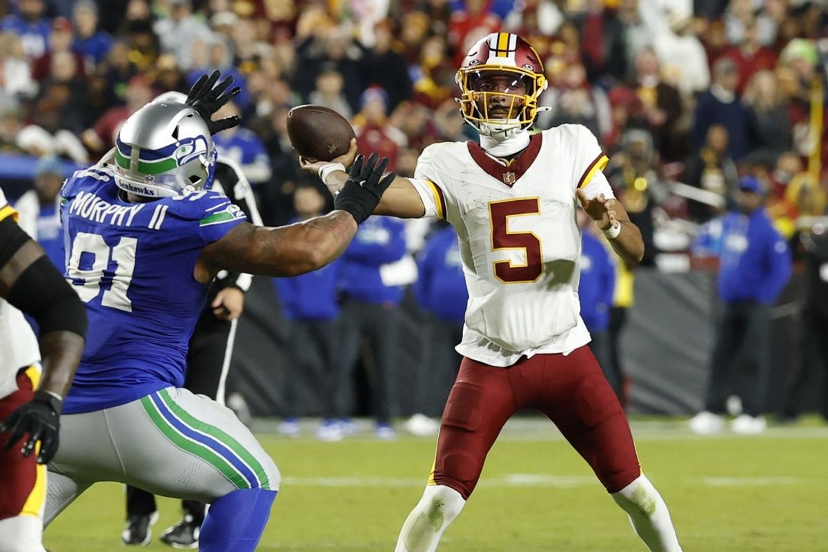 Nov 2, 2025; Landover, Maryland, USA; Washington Commanders quarterback Jayden Daniels (5) passes the ball as Seattle Seahawks defensive tackle Byron Murphy II (91) chases in the second quarter at Northwest Stadium. Mandatory Credit: Geoff Burke-Imagn Images
