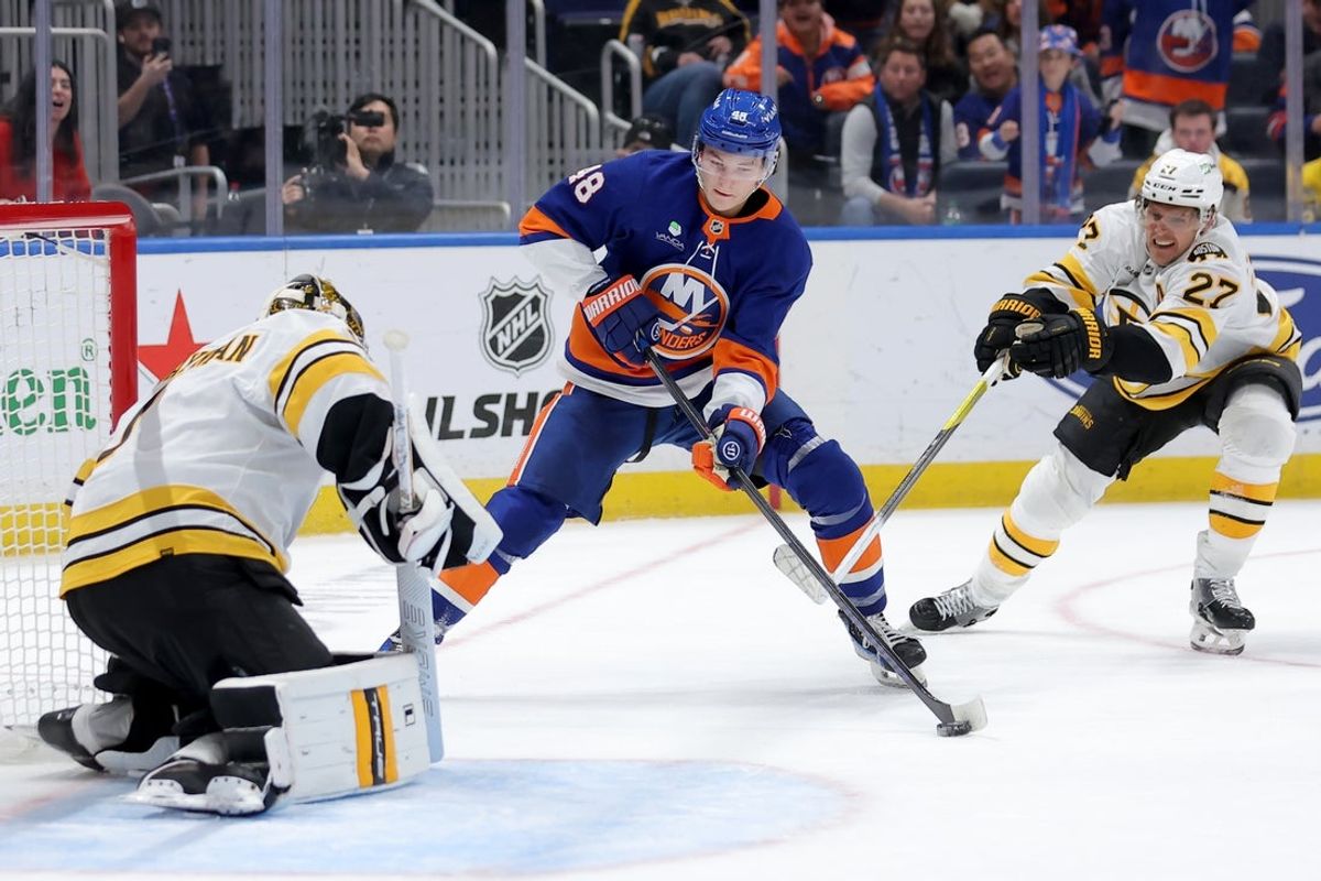 Nov 4, 2025; Elmont, New York, USA; New York Islanders defenseman Matthew Schaefer (48) takes a shot against Boston Bruins goaltender Jeremy Swayman (1) and defenseman Hampus Lindholm (27) during overtime at UBS Arena. Mandatory Credit: Brad Penner-Imagn Images