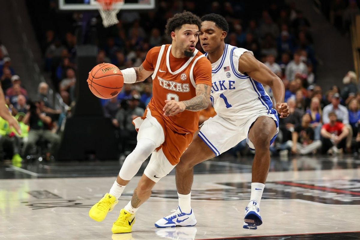 Nov 4, 2025; Charlotte, North Carolina, USA; Texas Longhorns guard Jordan Pope (0) drives the ball around Duke Blue Devils guard Caleb Foster (1) during the second half of the Dick Vitale’s Invitational game at Spectrum Center. Mandatory Credit: Cory Knowlton-Imagn Images