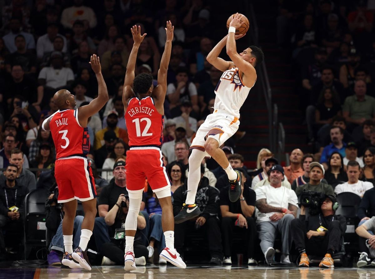Nov 6, 2025; Phoenix, Arizona, USA; Phoenix Suns guard Devin Booker (1) shoots the ball against Los Angeles Clippers guard Cam Christie (12) and Chris Paul (3) in the first half at the Mortgage Matchup Center. Mandatory Credit: Mark J. Rebilas-Imagn Images