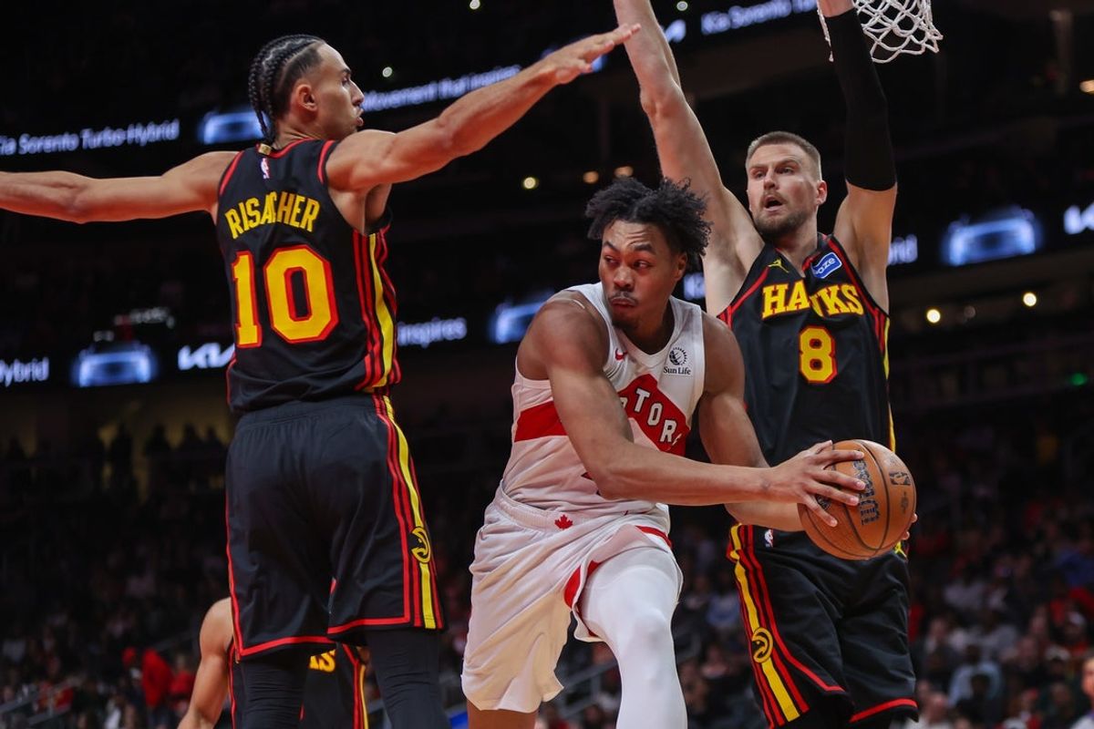 Nov 7, 2025; Atlanta, Georgia, USA; Toronto Raptors forward Scottie Barnes (4) passes around Atlanta Hawks forward Zaccharie Risacher (10) and center Kristaps Porzingis (8) in the fourth quarter at State Farm Arena. Mandatory Credit: Brett Davis-Imagn Images