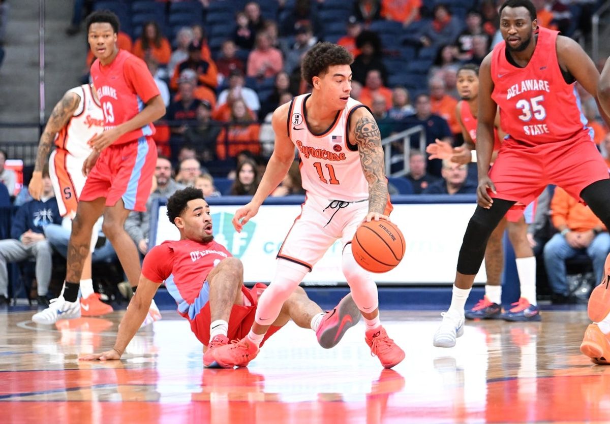 Nov 8, 2025; Syracuse, New York, USA; Syracuse Orange guard Naithan George (11) handles the ball as Delaware State Hornets guard Ponce James (1) falls on the floor in the first half  at the JMA Wireless Dome. Mandatory Credit: Mark Konezny-Imagn Images