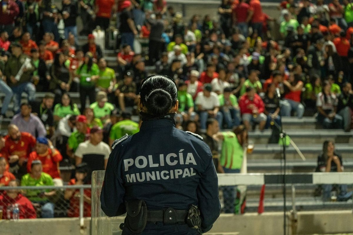 A Juárez municipal police officer keeps watch over Bravos’ fan club “El Cartel” during halftime of FC Juárez’s final regular season match against Querétaro at Benito Juárez Olympic Stadium in Juárez, Mexico, on Nov. 7, 2025. FC Juárez lost 2-1 but secured a play-in spot for a chance to reach the Liga MX playoffs.