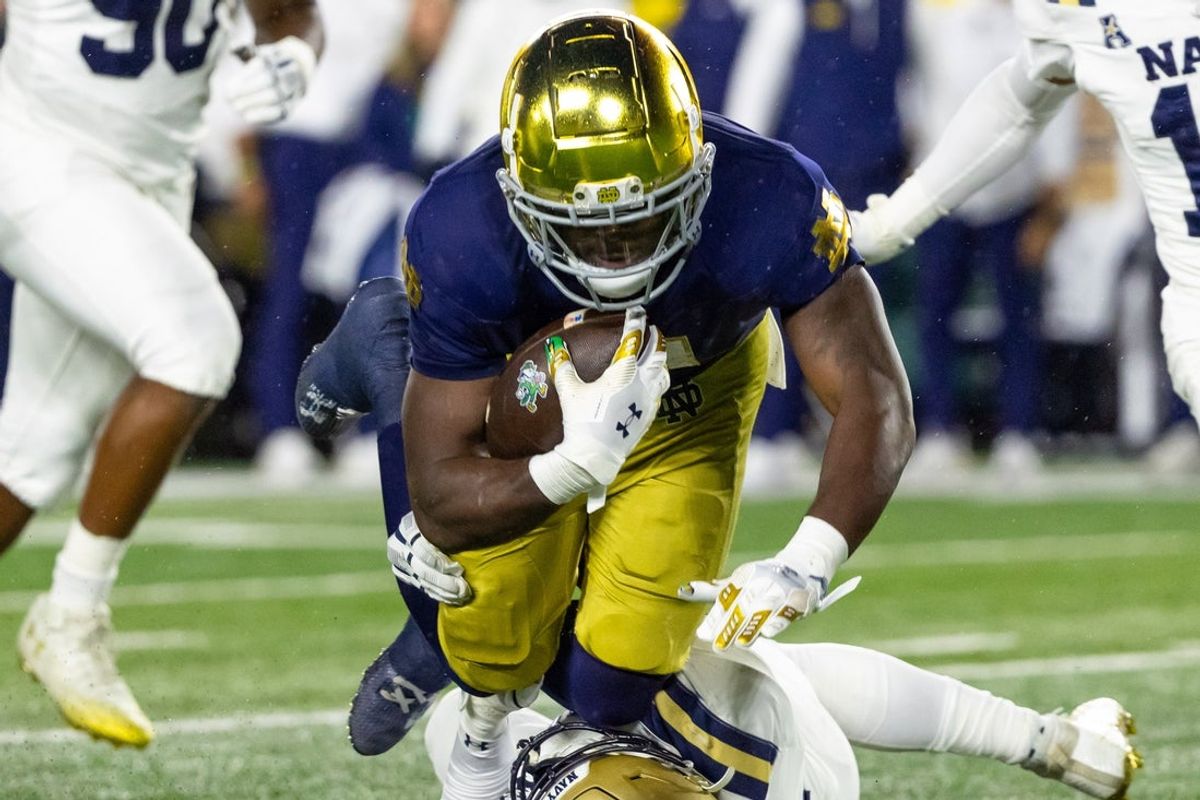 Nov 8, 2025; South Bend, Indiana, USA; Notre Dame Fighting Irish running back Jeremiyah Love (4) runs the ball as Navy Midshipmen linebacker Marcanthony Parker (56) tackles him during the first half at Notre Dame Stadium. Mandatory Credit: Michael Caterina-Imagn Images