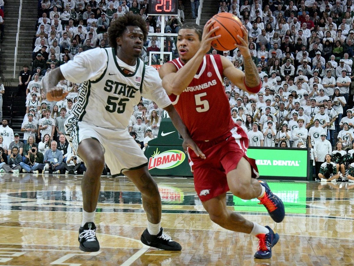 Nov 8, 2025; East Lansing, Michigan, USA;  Arkansas Razorbacks guard Darius Acuff Jr. (5) drives with Michigan State Spartans forward Coen Carr (55) defending during the first half at Jack Breslin Student Events Center. Mandatory Credit: Dale Young-Imagn Images