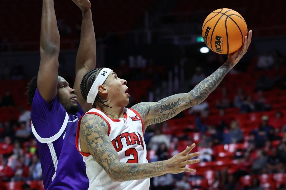 Nov 8, 2025; Salt Lake City, Utah, USA; Utah Utes guard Terrence Brown (2) lays the ball up against Weber State Wildcats forward Edwin Suarez Jr. (0) during the second half at Jon M. Huntsman Center. Mandatory Credit: Rob Gray-Imagn Images