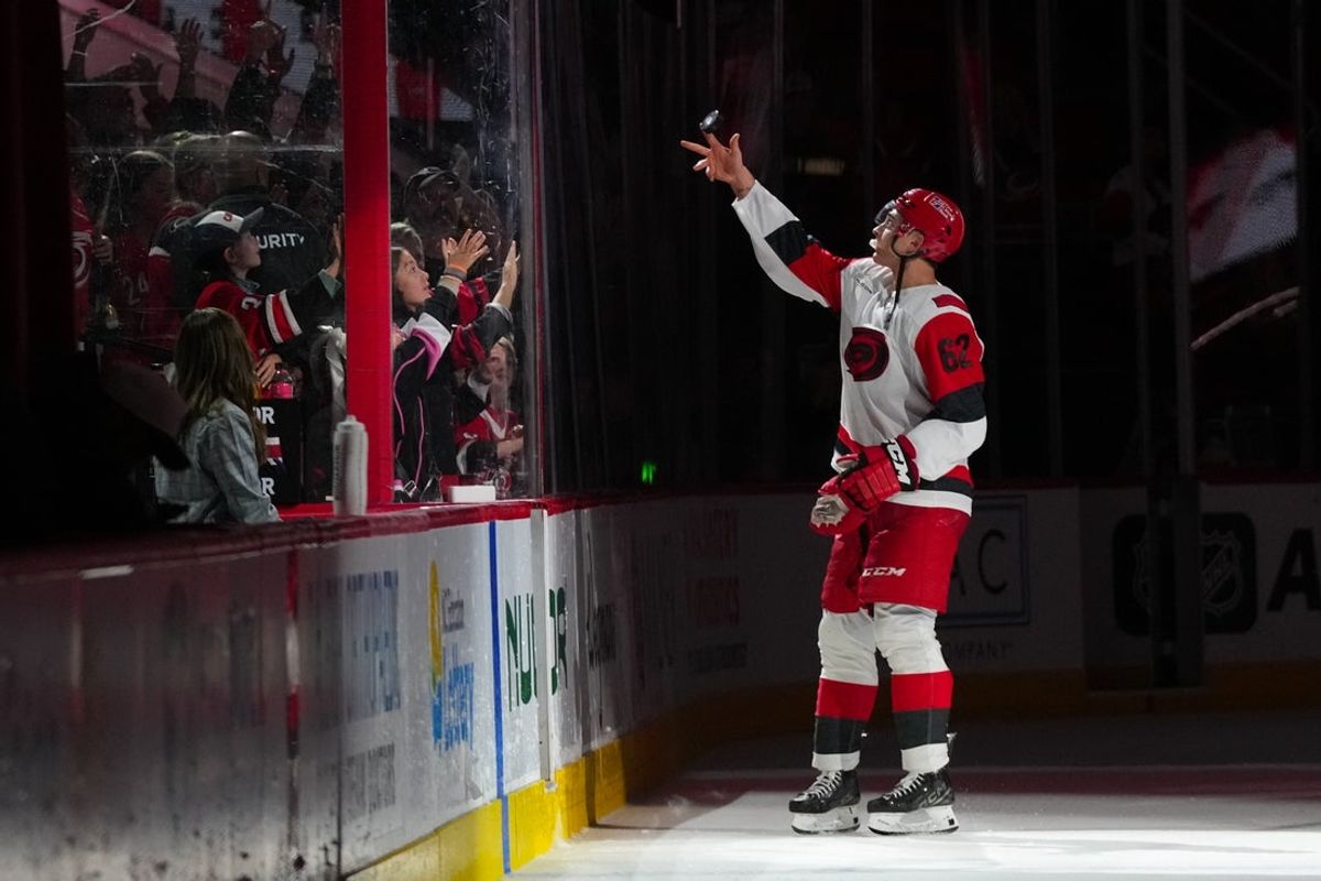Nov 8, 2025; Raleigh, North Carolina, USA;  Carolina Hurricanes defenseman Charles Alexis Legault (62) tosses a puck to the fans after their victory against the Buffalo Sabres at Lenovo Center. Mandatory Credit: James Guillory-Imagn Images