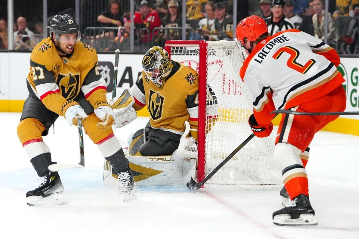 Nov 8, 2025; Las Vegas, Nevada, USA; Vegas Golden Knights goaltender Akira Schmid (40) makes a save against Anaheim Ducks defenseman Jackson Lacombe (2) behind defenseman Shea Theodore (27) during the first period at T-Mobile Arena. Mandatory Credit: Stephen R. Sylvanie-Imagn Images