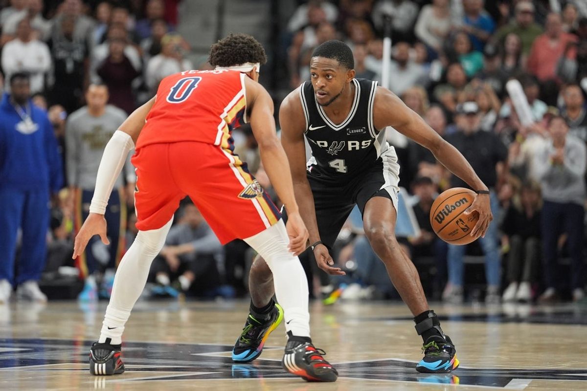 Nov 8, 2025; San Antonio, Texas, USA;  San Antonio Spurs guard De'Aaron Fox (4) dribbles against New Orleans Pelicans guard Jeremiah Fears (0) in the second half at Frost Bank Center. Mandatory Credit: Daniel Dunn-Imagn Images