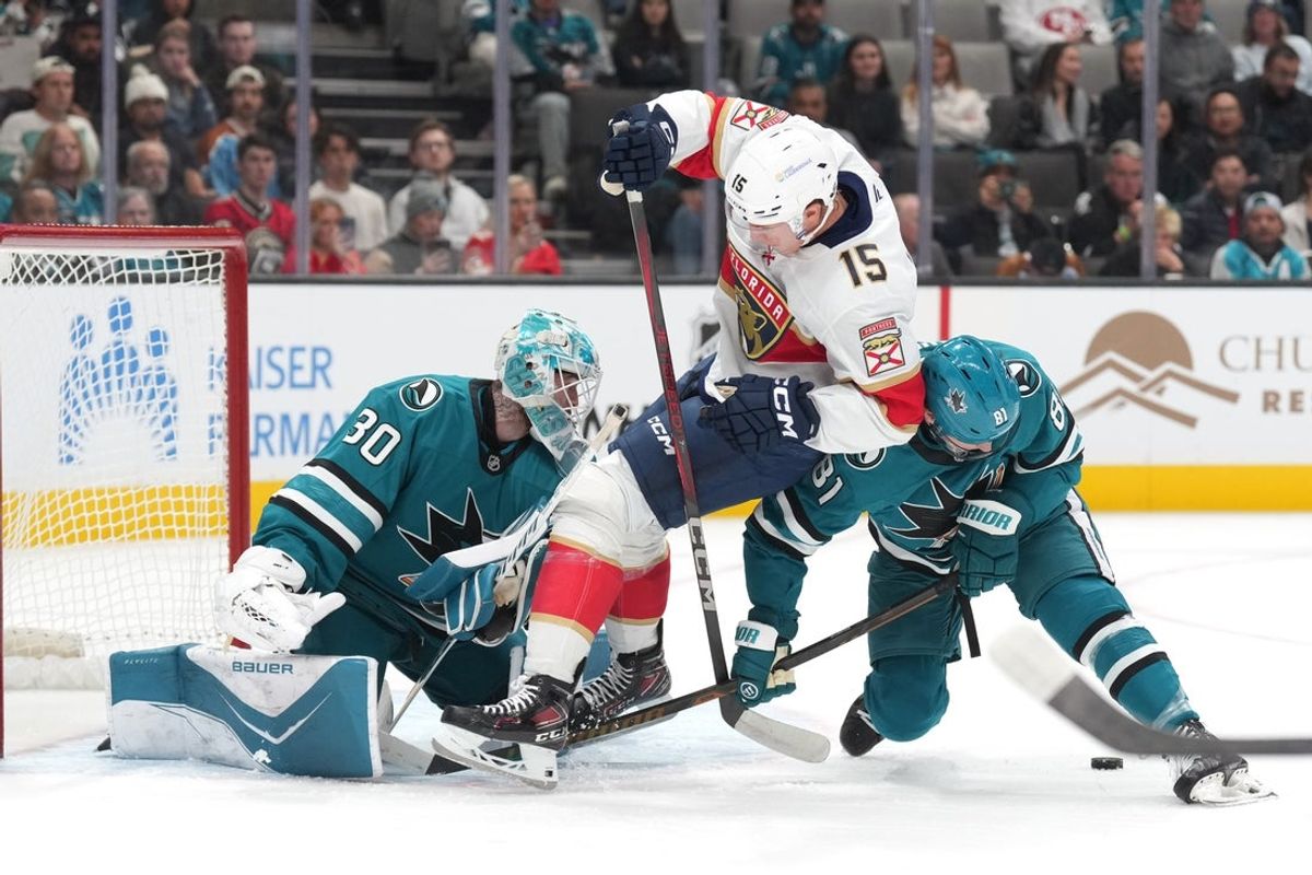Nov 8, 2025; San Jose, California, USA; Florida Panthers center Anton Lundell (15) is upended by San Jose Sharks right wing Adam Gaudette (81) with goaltender Yaroslav Askarov (30) during the first period at SAP Center at San Jose. Mandatory Credit: Darren Yamashita-Imagn Images
