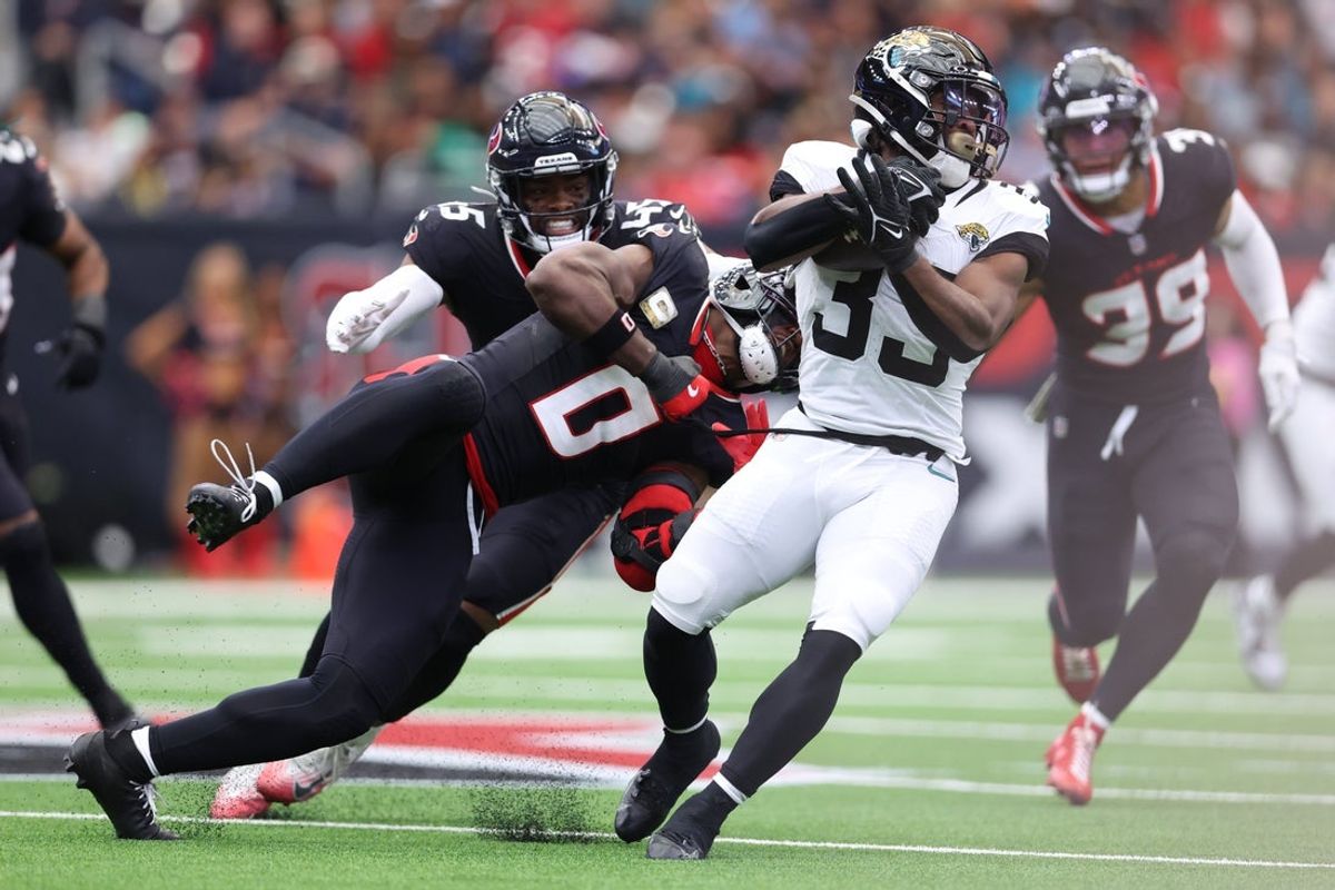 Nov 9, 2025; Houston, Texas, USA; Jacksonville Jaguars running back Bhayshul Tuten (33) is tackled by Houston Texans linebacker Azeez Al-Shaair (0) during the first half at NRG Stadium. Mandatory Credit: Troy Taormina-Imagn Images