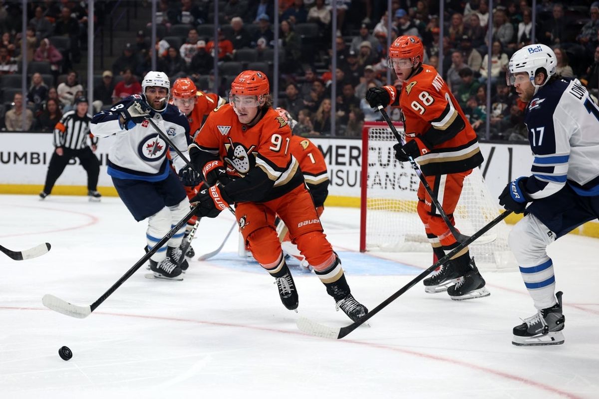 Nov 9, 2025; Anaheim, California, USA;  Anaheim Ducks center Leo Carlsson (91) controls the puck against Winnipeg Jets center Adam Lowry (17) during the first period at Honda Center. Mandatory Credit: Kiyoshi Mio-Imagn Images