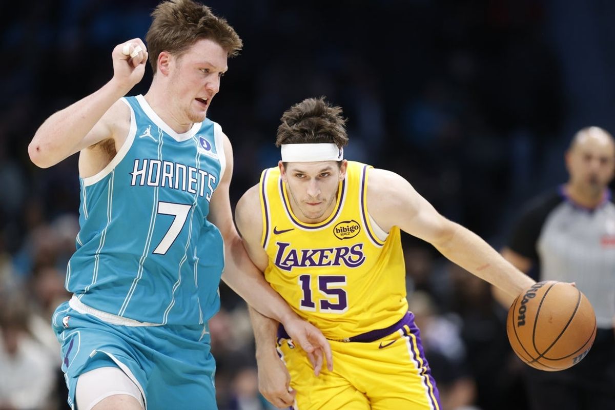 Nov 10, 2025; Charlotte, North Carolina, USA; Los Angeles Lakers guard Austin Reaves (15) tries to drive past Charlotte Hornets guard/forward Kon Knueppel (7) during the second quarter at Spectrum Center. Mandatory Credit: Brian Westerholt-Imagn Images